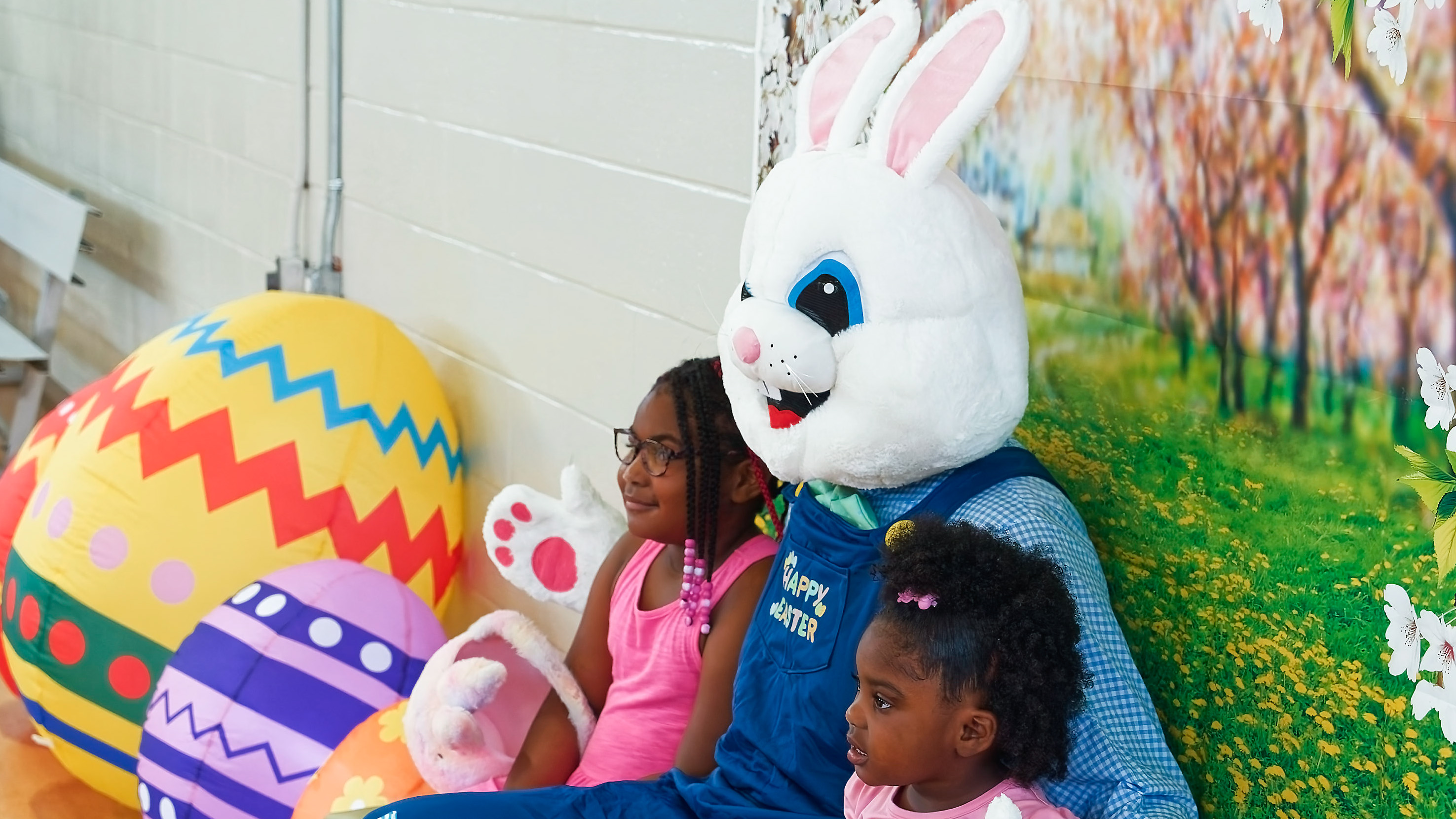 the Biltmore bunny posing with 2 children with large decorative eggs nearby 