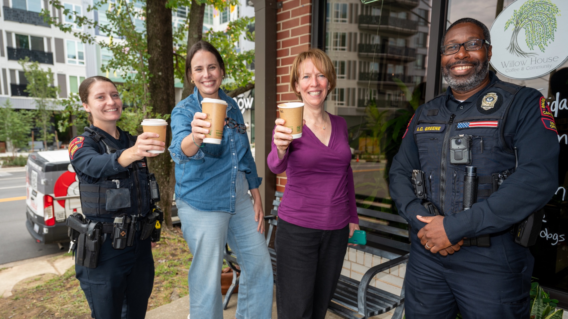 Police officer holding coffee cup next to storefront