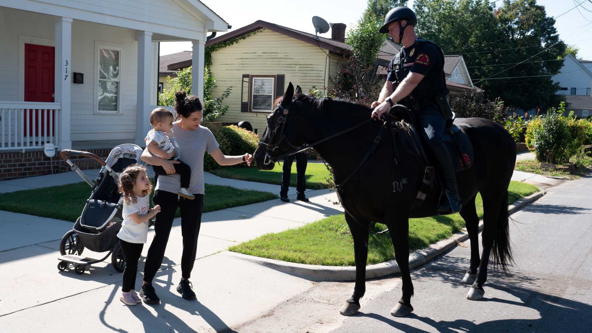 A mother and her two kids watch a mounted patrol unit