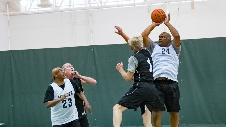 four men playing basketball in the senior games with one shooting a jump shot 