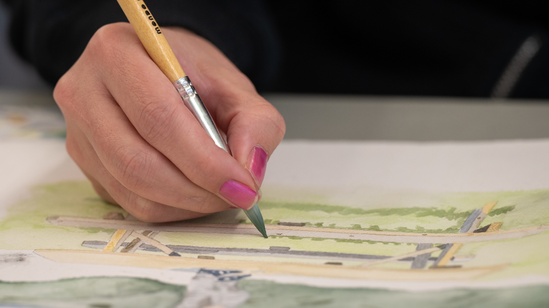 hand with pink nails painting a watercolor painting