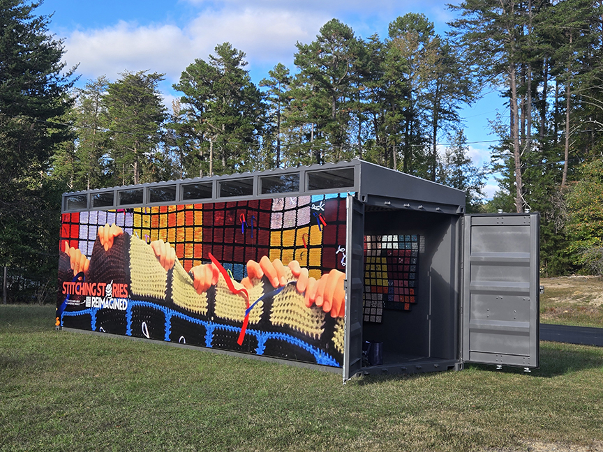 A colorful shipping container, covered in artwork, rests in an outdoor setting