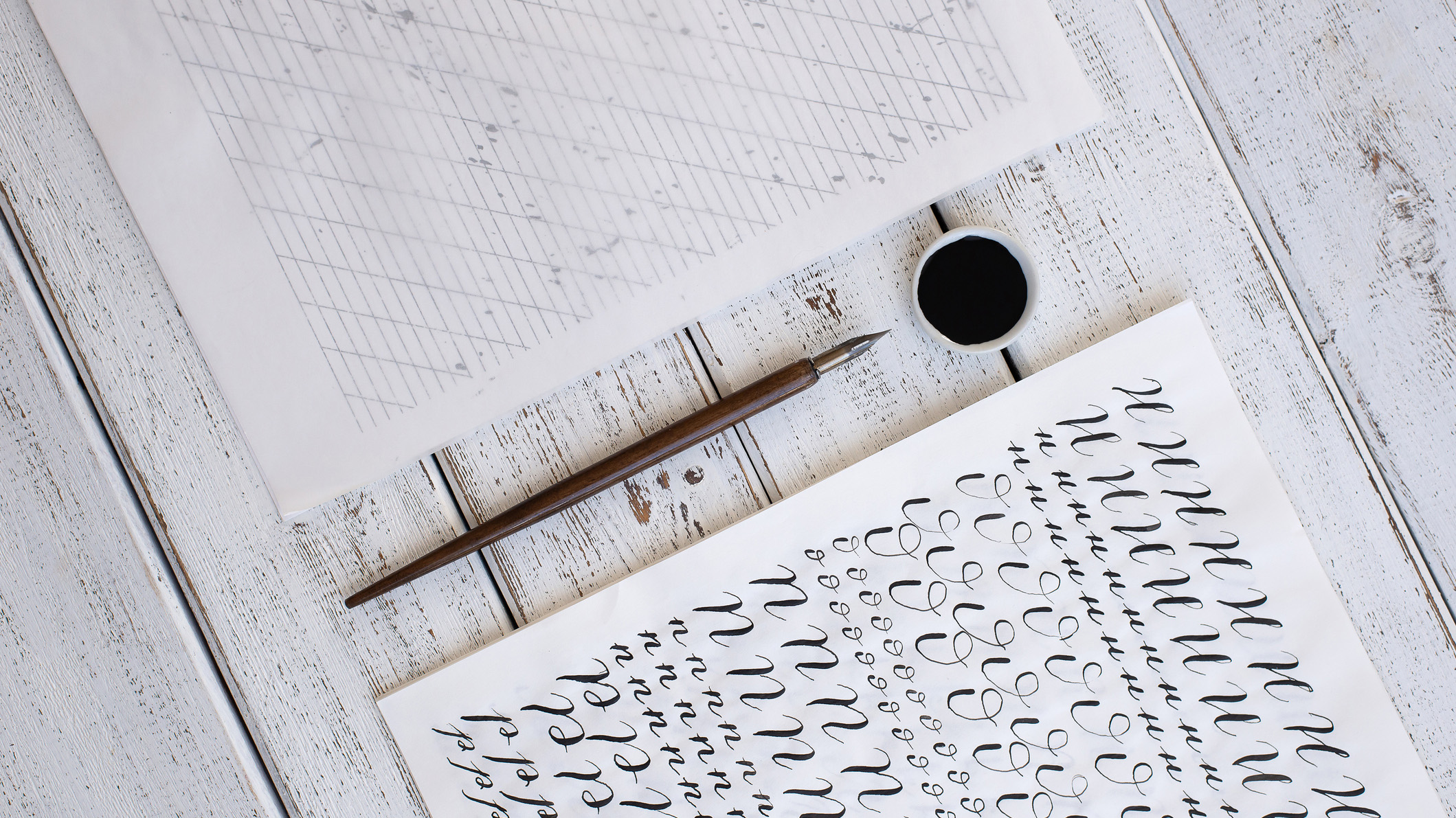 calligraphy sheets, nibs, paper, ink on a wooden background