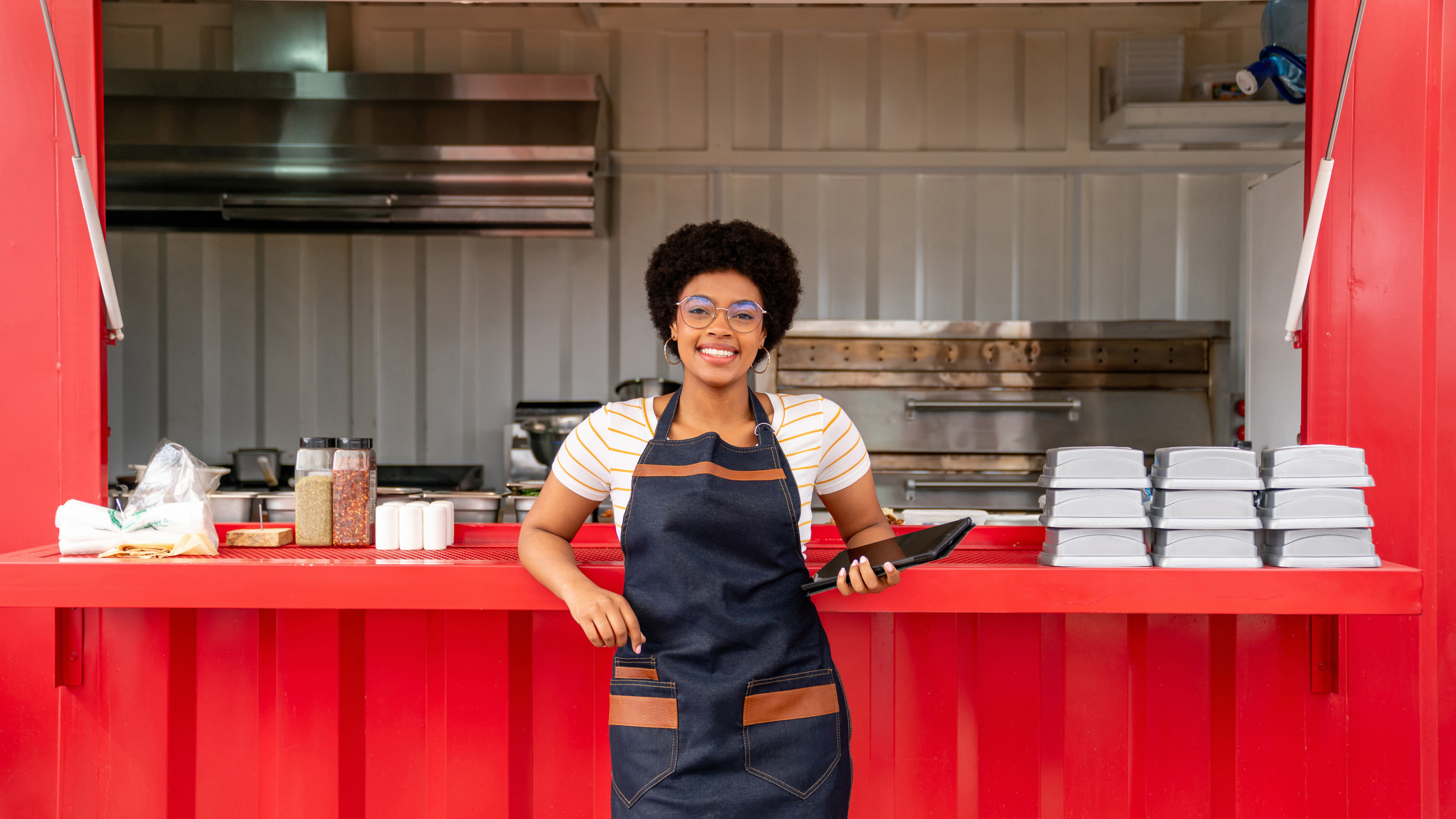a food vender smiling while standing in front of their food truck