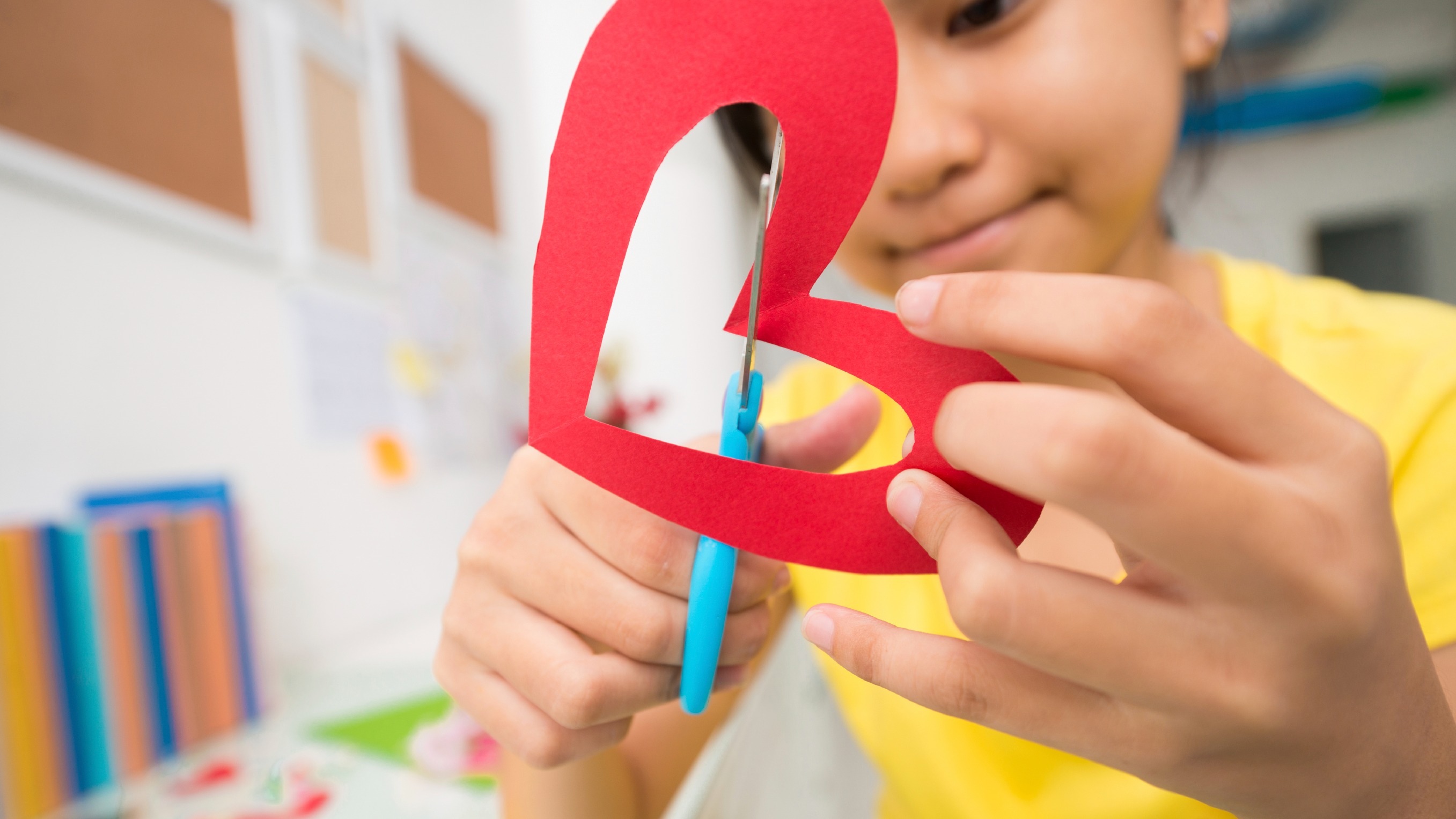 a kid crafting a heart out of paper