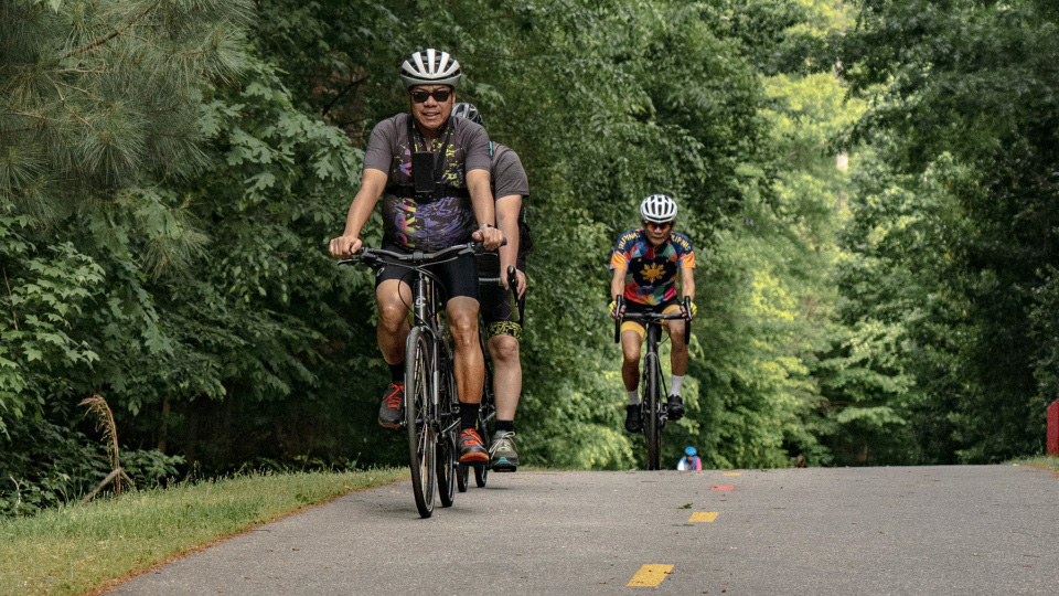 a group of people riding their bikes on a greenway trail