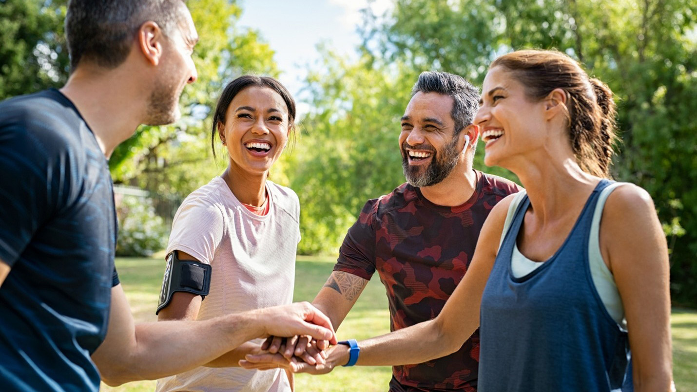people smiling and huddled up wearing fitness attire outdoors
