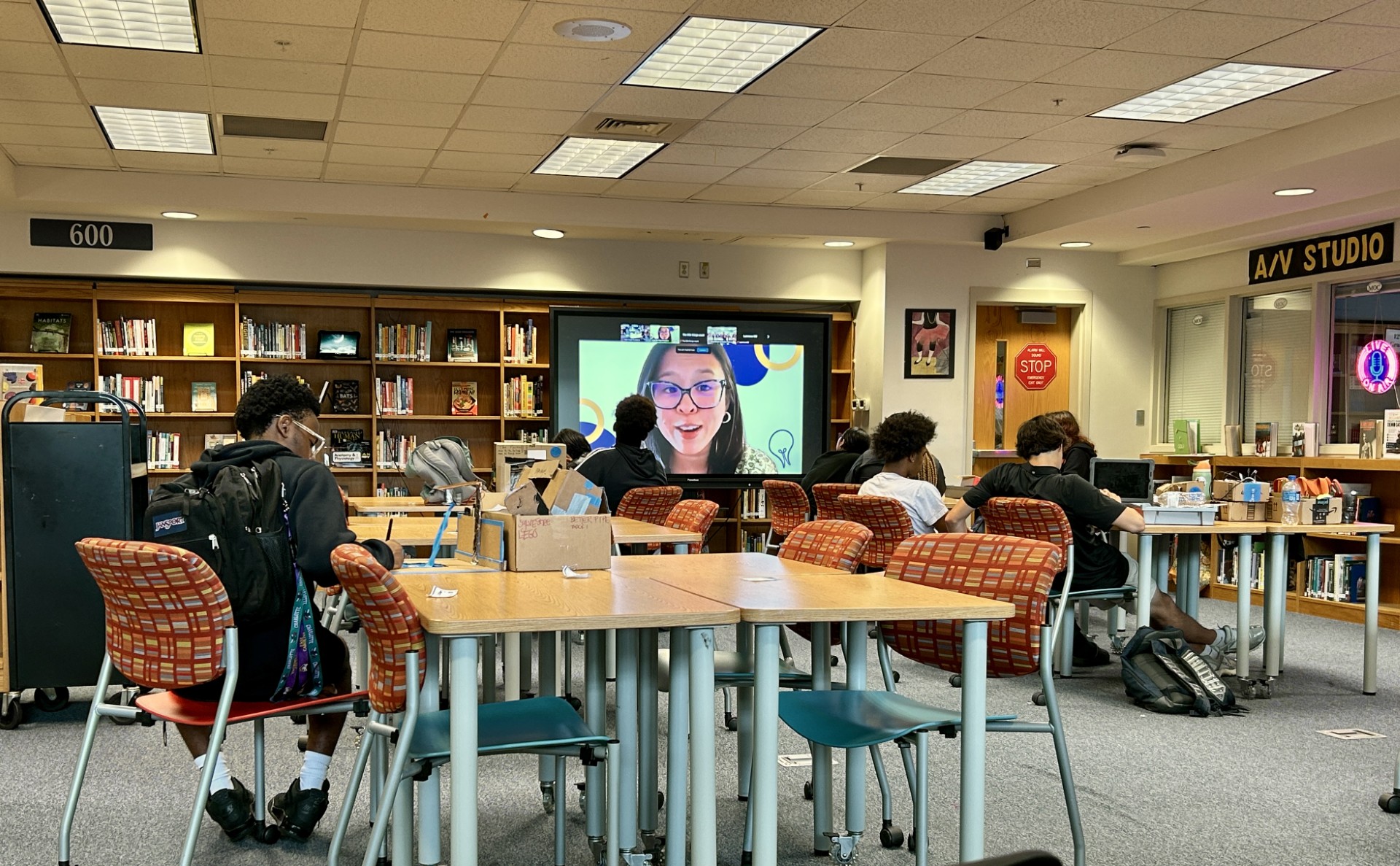 students sitting at open tables in front of meeting projector
