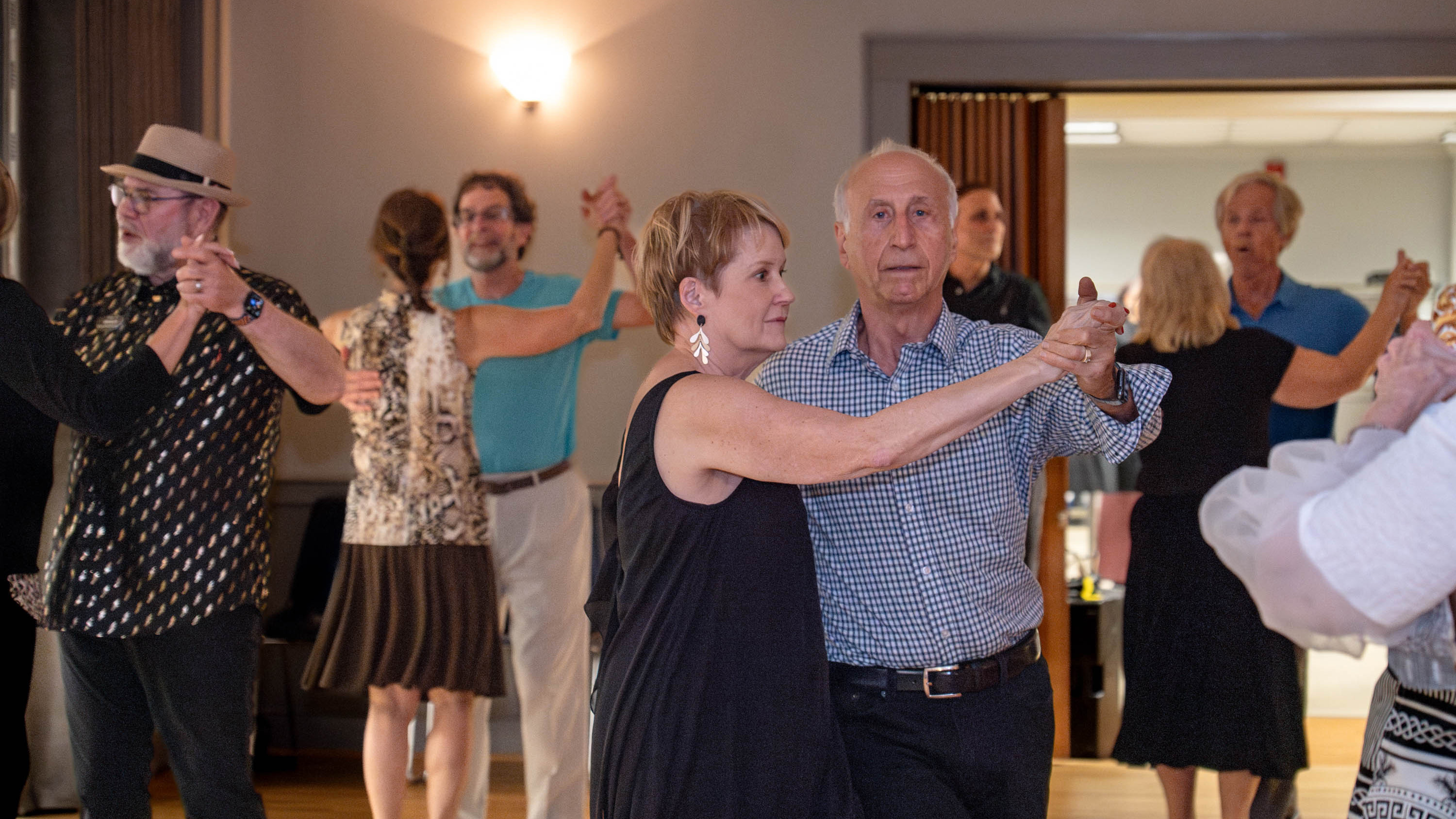 couples doing ballroom dancing in a room with other couples