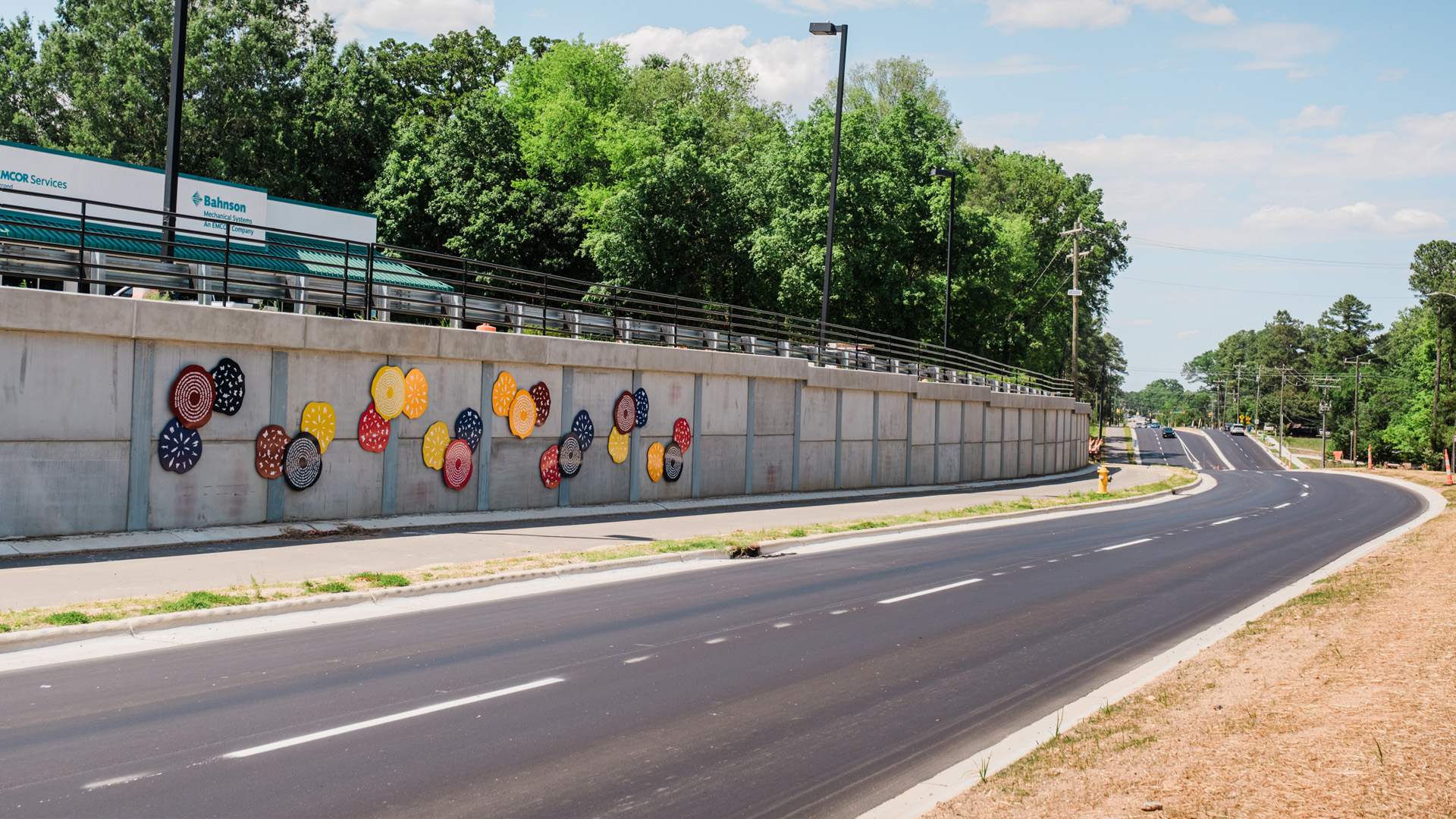 Colorful discs make up public art along a wall beside a road