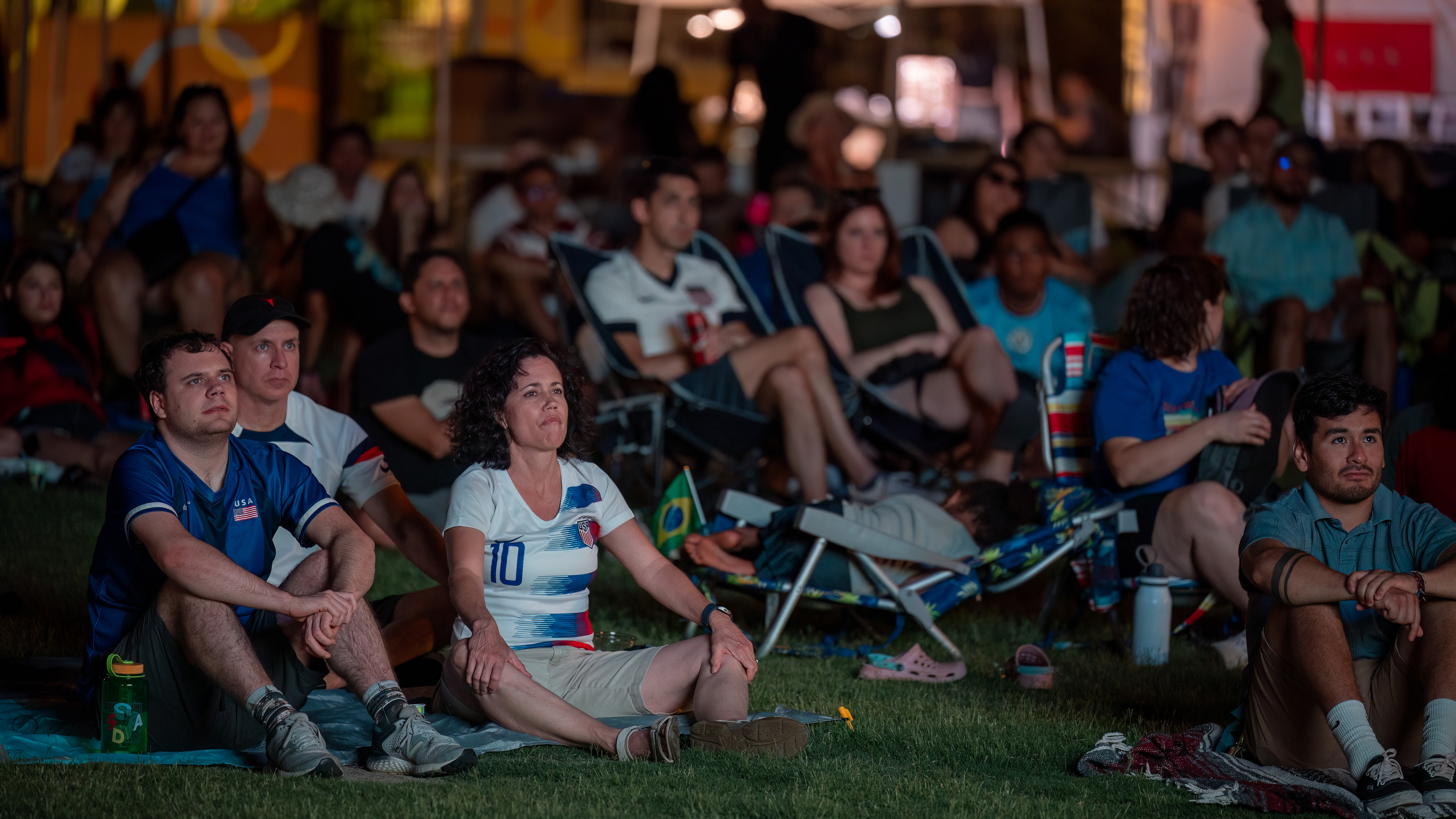 people outdoors watching a soccer game wearing their favorite team's attire