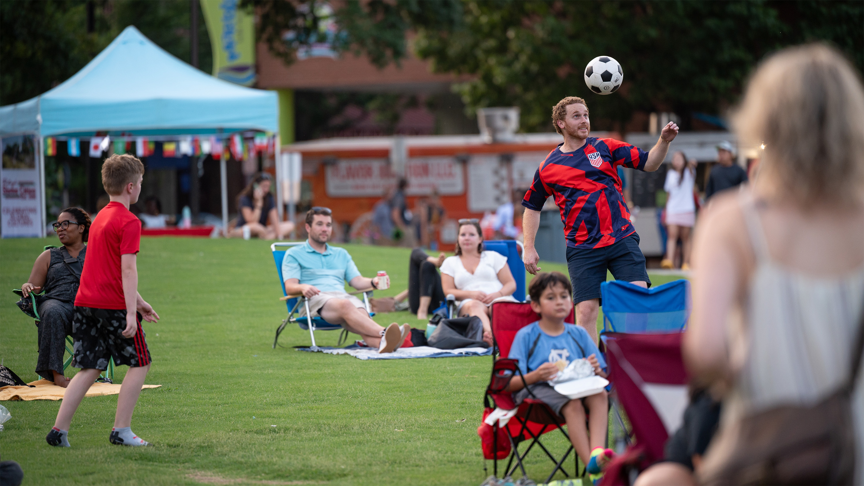 people outdoors watching a soccer game wearing their favorite team's attire