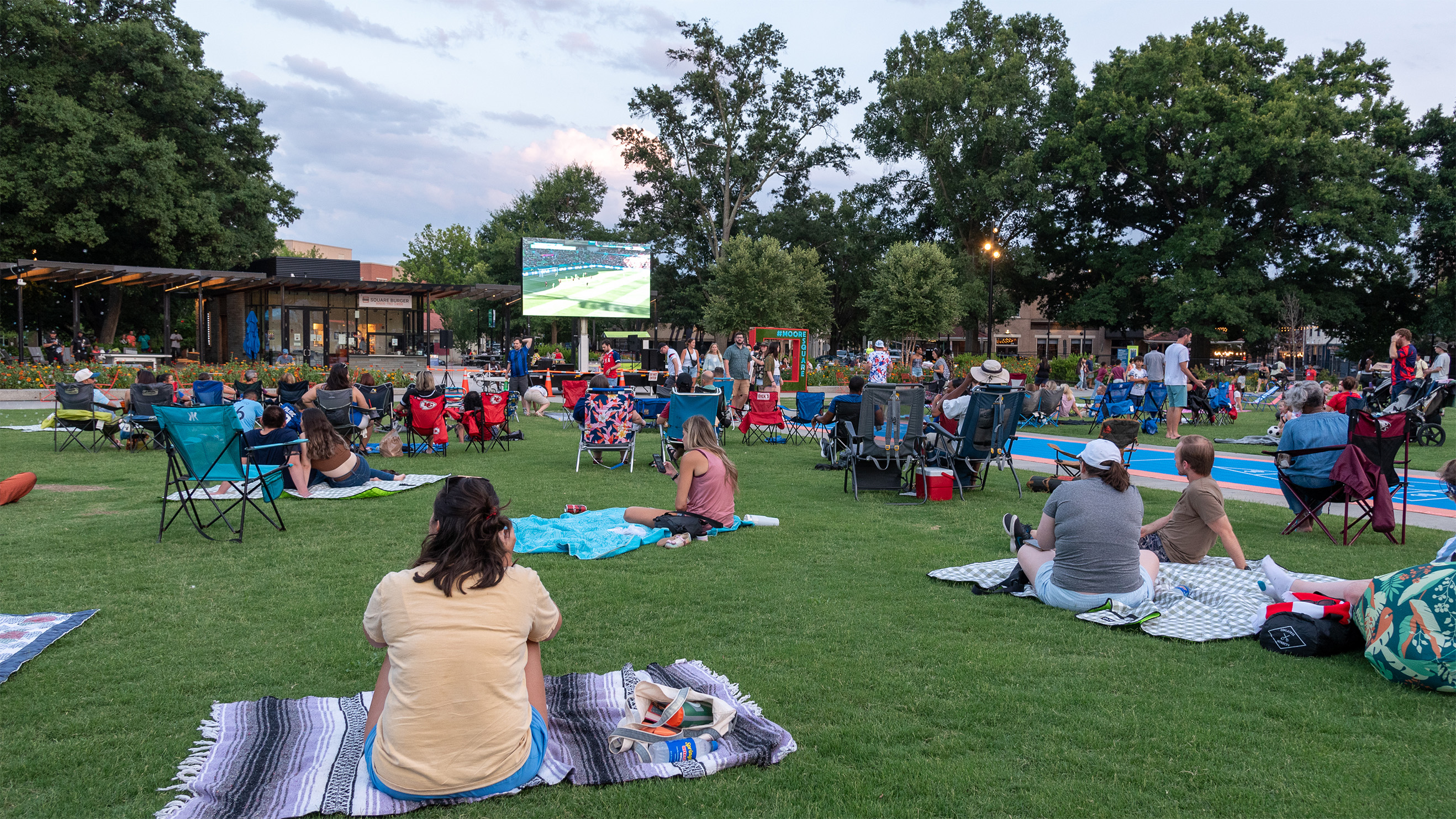 an event with people sitting on blankets watching an ourdoor movies