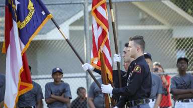 police explorer presenting the North Carolina state flag and the United States of America flag during a ceremony.