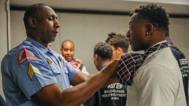 Raleigh Police Sergeant teach a young man how to tie a tie