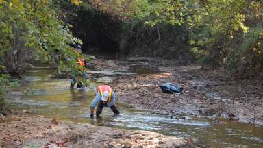 A volunteer picks up trash in a Raleigh stream to help reduce water pollution in our area.