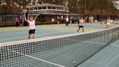Tennis players hitting balls over the net