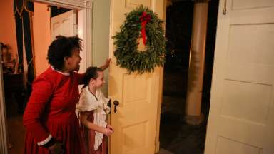 View of woman and child opening door of Mordecai House for holiday tour