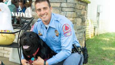Male police officer smiling and hugging dog