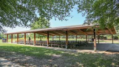 A very large picnic shelter with several tables located near the restrooms at Anderson Point Park