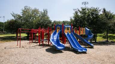 Baileywick Park playground shot including multiple slides, monkey bars and a woodchip surface. 