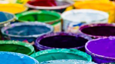 Paint cans ranging in color from blue, white, green, purple and yellow