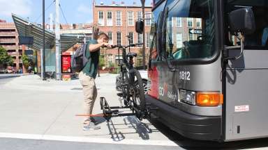 man loading bike on bus rack