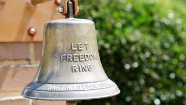 A bell which reads &quot;let freedom ring&quot; at the MLK Gardens