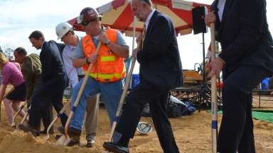 people in hardhats shoveling into dirt during a groundbreaking