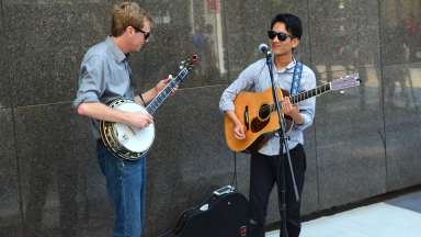 guitar player and banjo player performing in a plaza in downtown raleigh