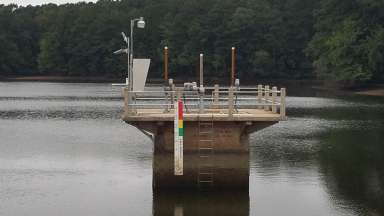 A riser structure in the middle of Lake Johnson to lower water levels
