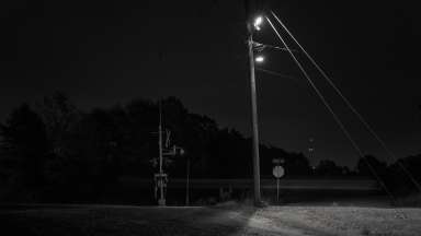 A black and white photograph of a street light and street sign at night by Adam Bellefeuil