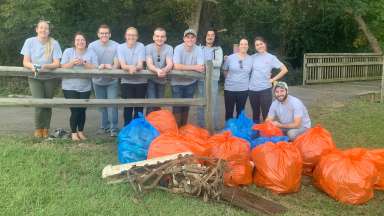 A group of volunteers standing with the trash they collected from a stream