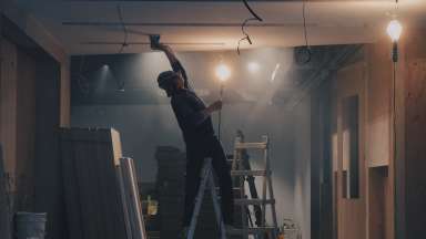 Man on ladder repairing white ceiling