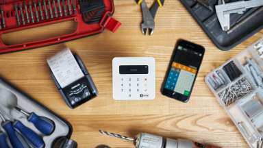 Receipt machine, calculator, and payment processor among tools on a wooden table