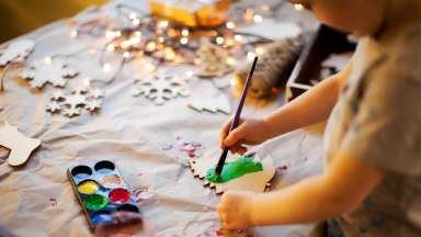 Kid painting wooden holiday ornament