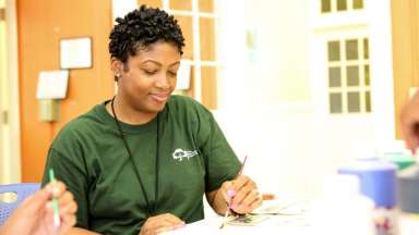 Woman in Raleigh parks staff shirt painting