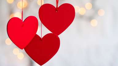 Red heart ornaments hanging with sparkling background