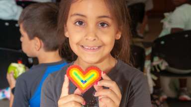 Little girl holding heart craft and smiling