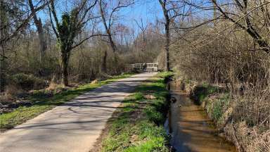 A stream and paved greenway path at Apollo Heights Park