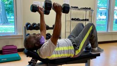 100-year-old man lifts weight on a fitness bench