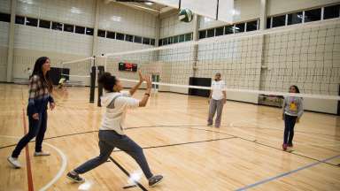 People indoors playing volleyball in gym