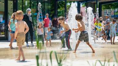 Kids running through water feature sprinklers