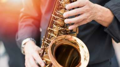 Saxophone, music instrument played by saxophonist player musician with hands on buttons