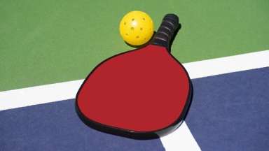 Pickleball paddle on court with pickleball