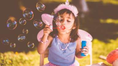 Little girl in fairy costume blowing bubbles