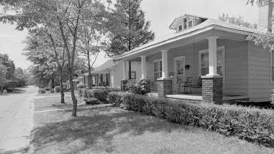 Black and white historic image of neighborhood with house and sidewalk