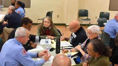 Police and community members gather at a table during a Police Advisory Board meeting