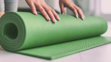 Hands unrolling green yoga mat