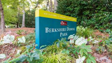 Sign for Berkshire Downs Park surrounded by plantings with trees in background
